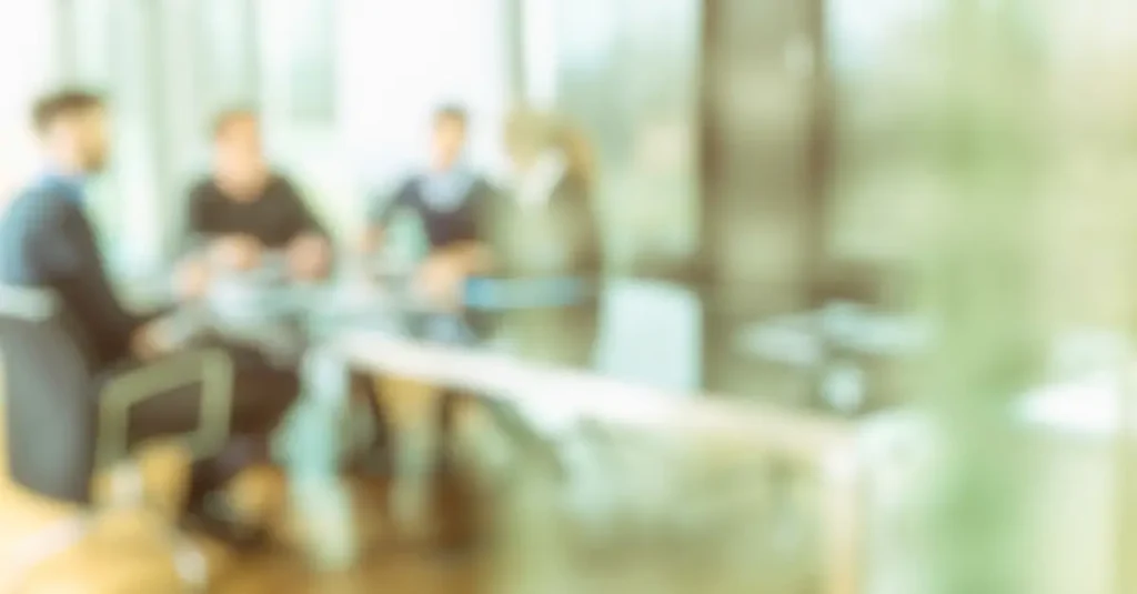 Imagen borrosa de una reunión de equipo centrada en deducciones fiscales y subvenciones.