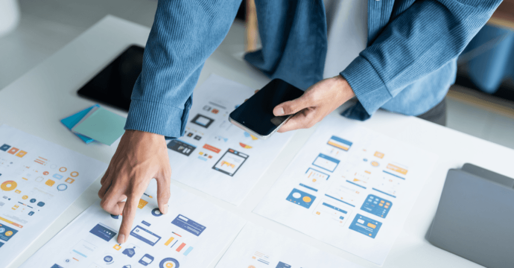 Asesor revisando documentación de deducciones fiscales por I+D+i mientras consulta información desde su móvil.