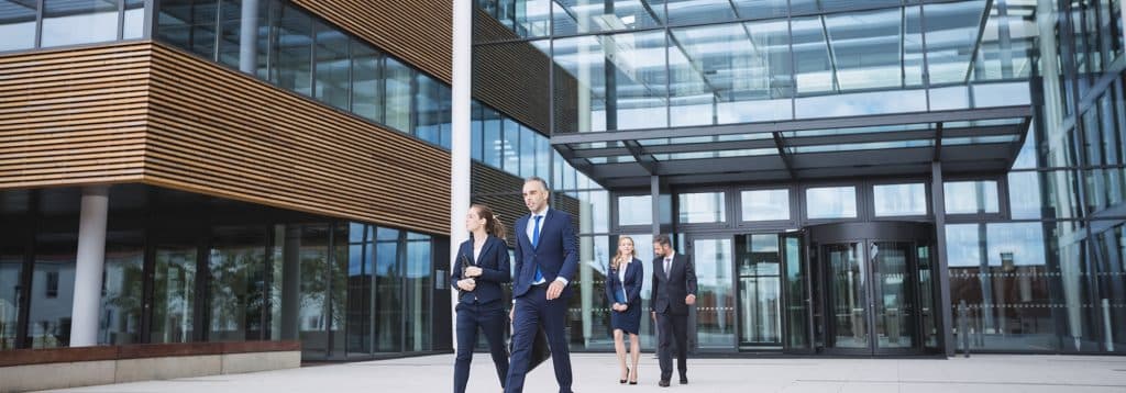 Grupo de personas saliendo de un edificio corporativo, representando el dinamismo empresarial y el compromiso con la innovación, sello PYME innovadora.