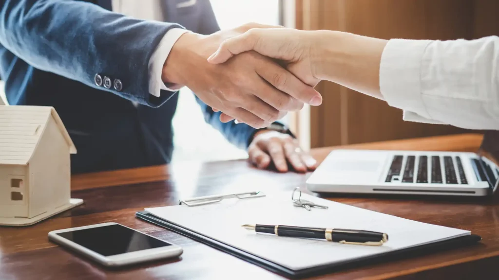 Apretón de manos entre dos profesionales durante la formalización de un acuerdo de Tax Lease destinado a la financiación de proyectos de I+D+i y al impulso de la innovación empresarial.